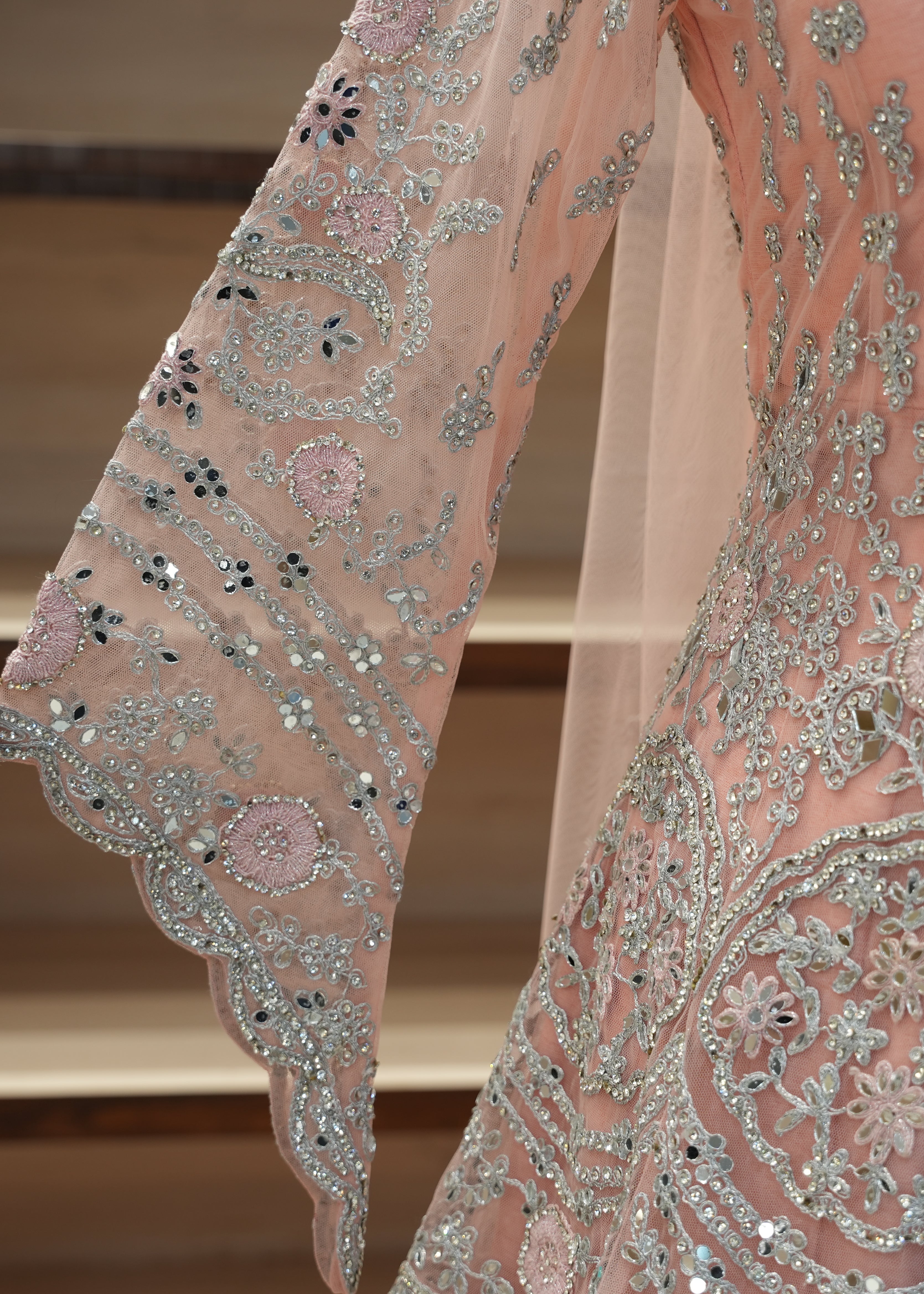 Close-up of a pink embroidered garment with intricate patterns and embellishments.