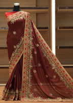Maroon saree with gold and red embroidery on a mannequin against a wooden background