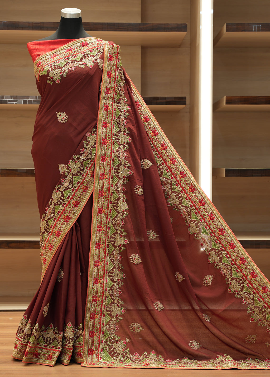 Brown saree with intricate gold and red embroidery on a wooden background