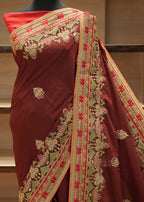 Maroon saree with intricate gold and red embroidery on a mannequin against a neutral background.