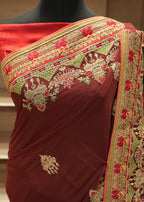 Maroon saree with gold and red embroidery on a mannequin against a neutral background