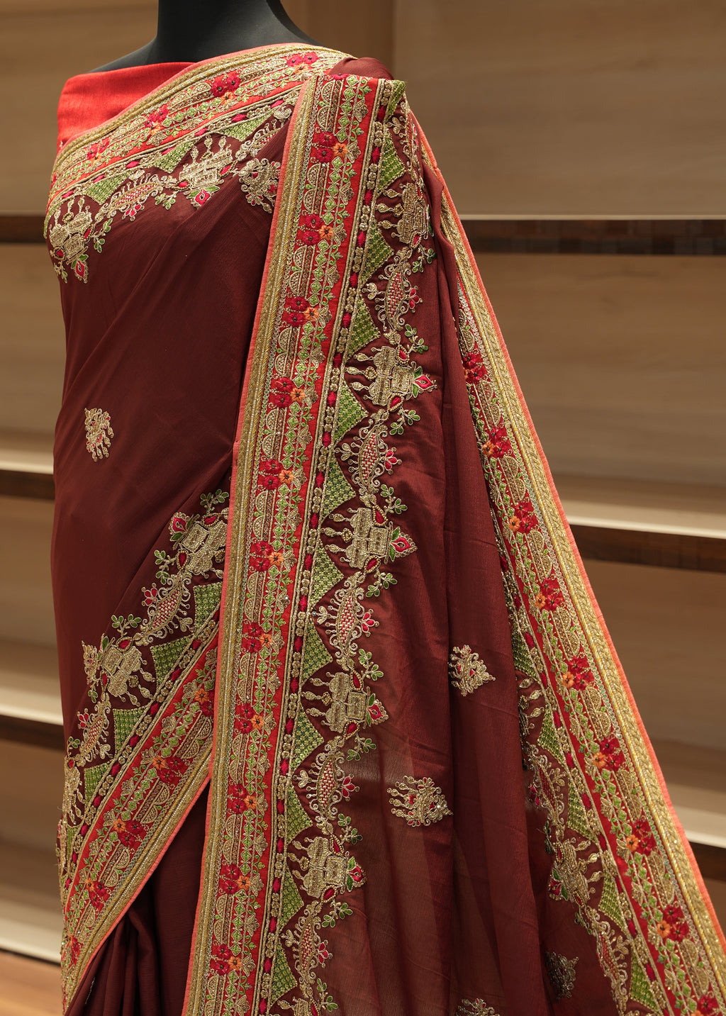 Maroon fabric with intricate green and red embroidery on a stand.