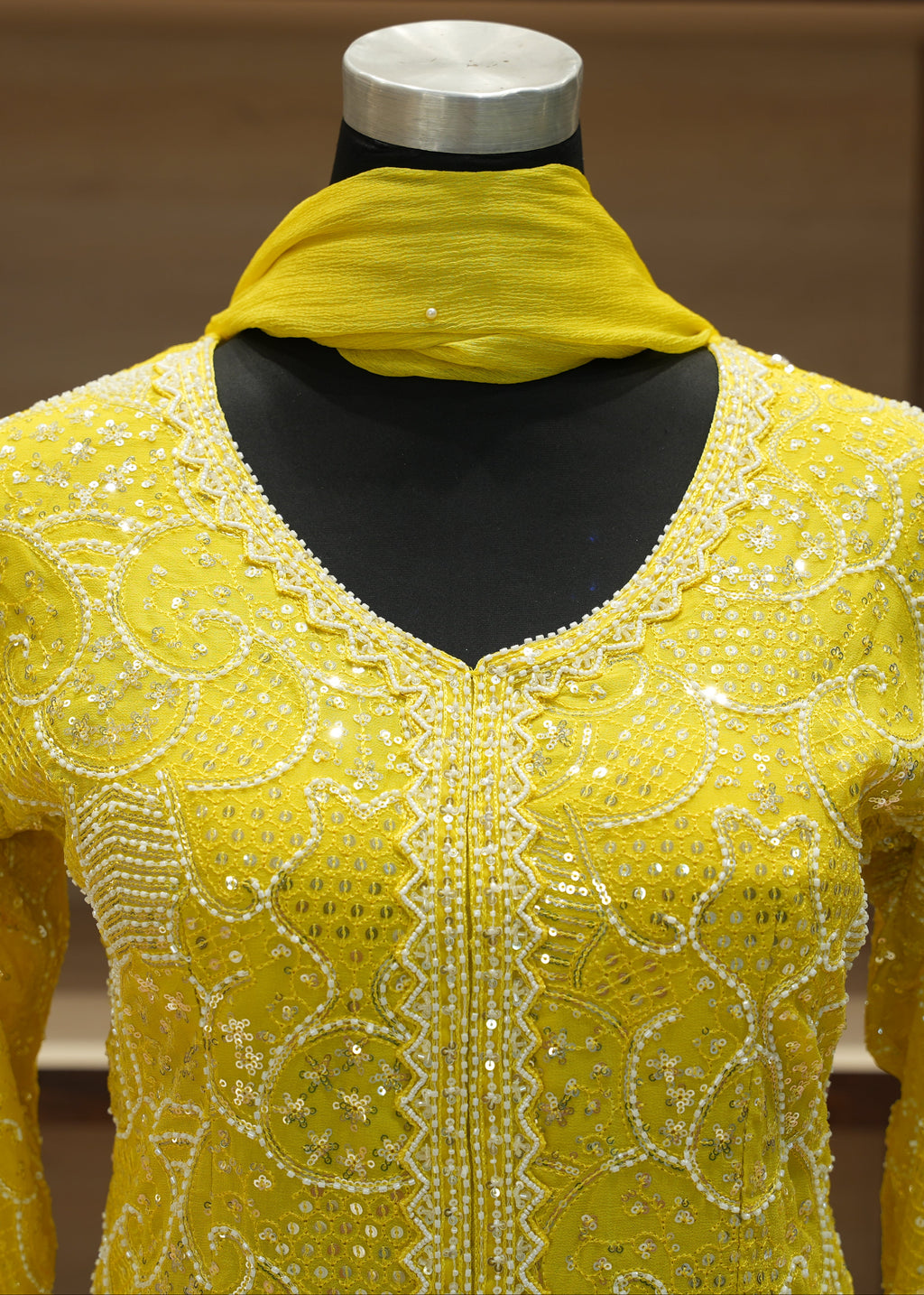 Yellow embroidered garment on a mannequin with a blurred background