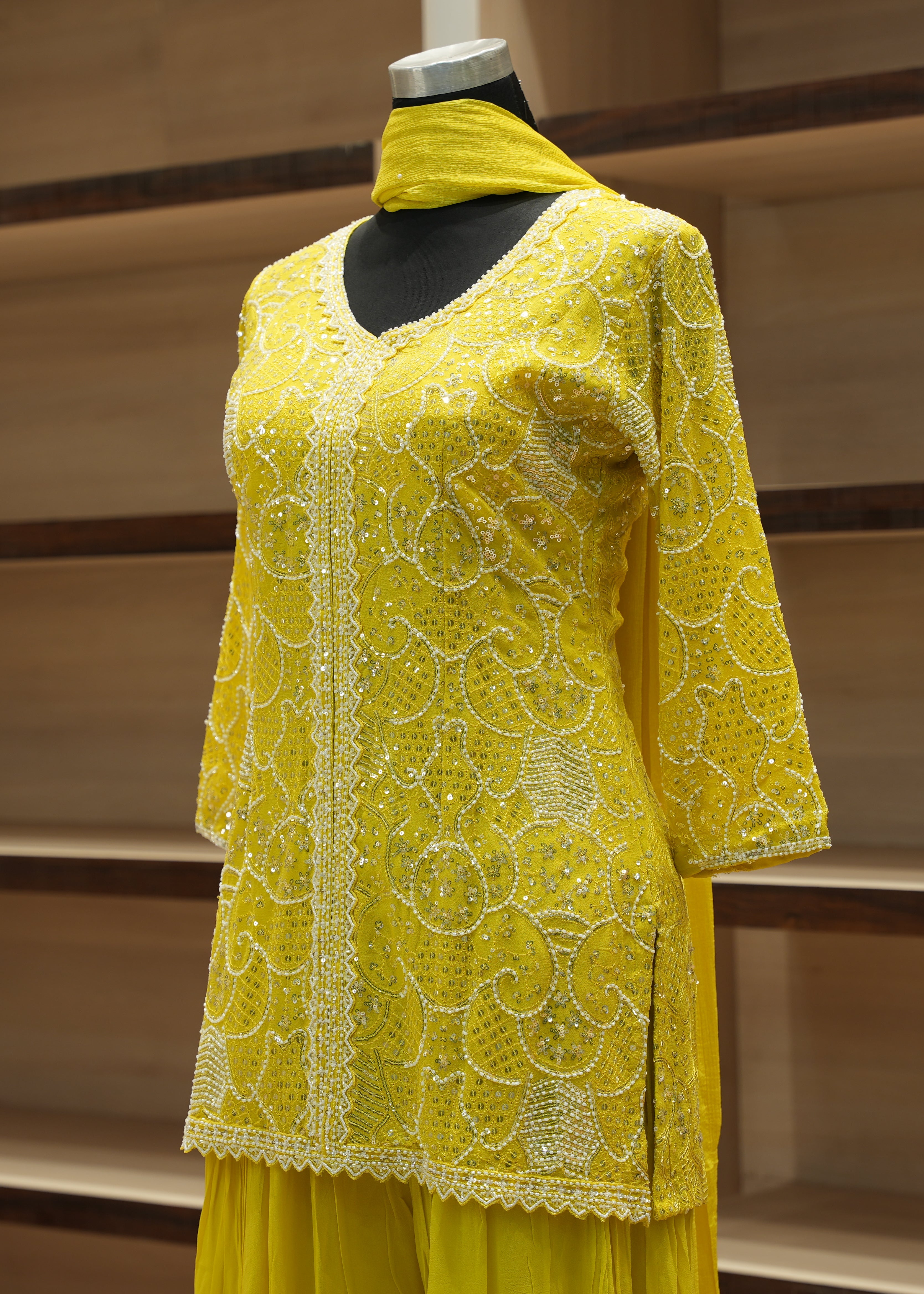 Yellow embroidered outfit on a mannequin against a wooden background