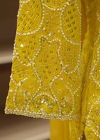 Close-up of a yellow fabric with intricate gold embroidery on a blurred background