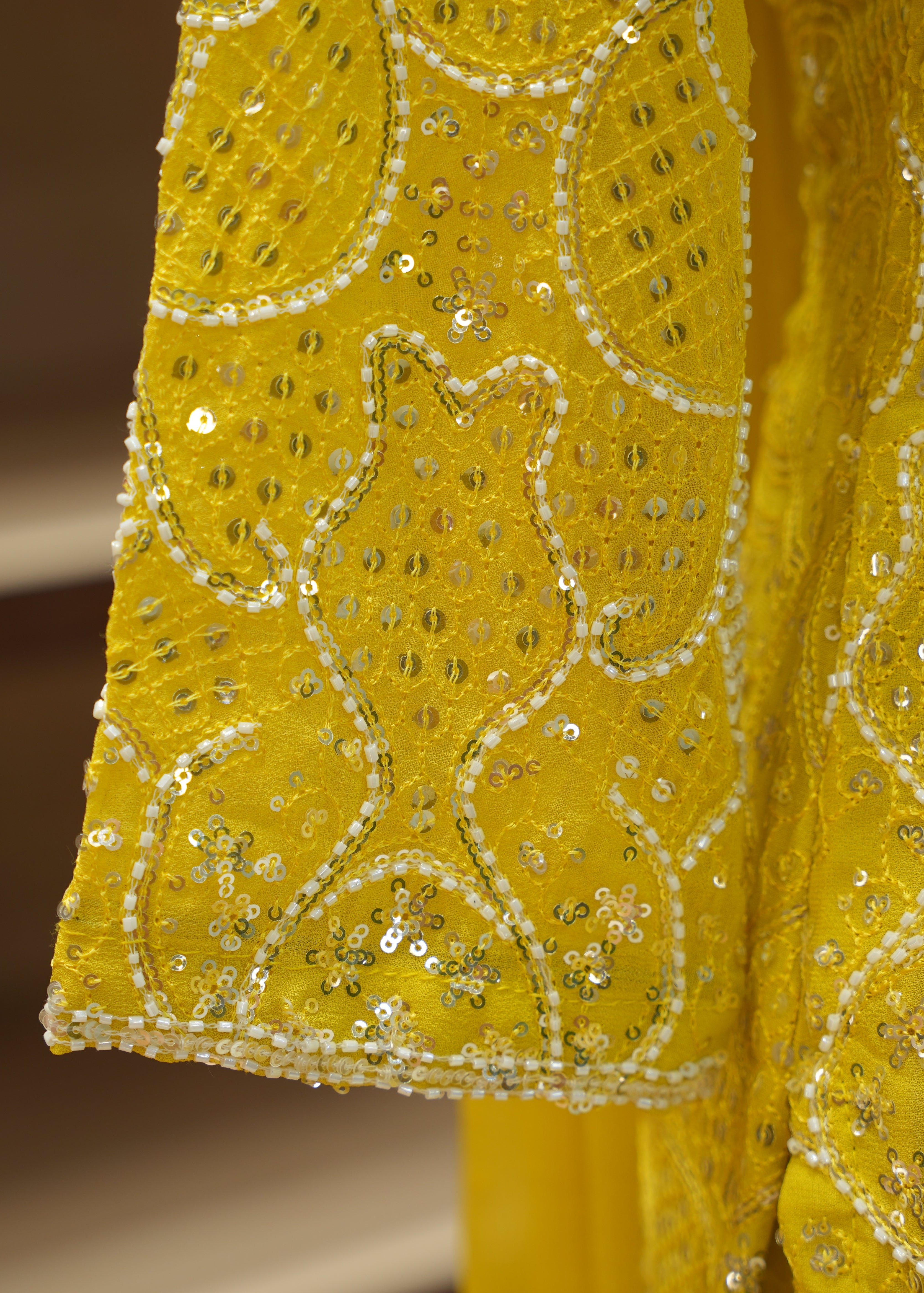 Close-up of a yellow fabric with intricate gold embroidery on a blurred background