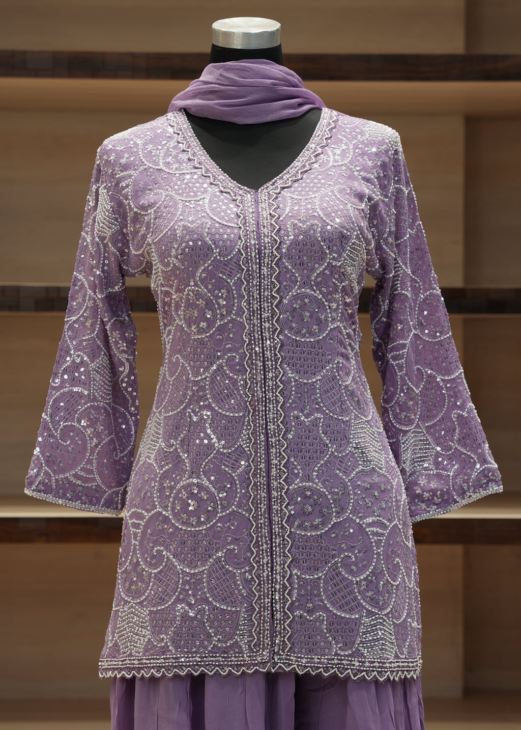 Purple embroidered dress on a mannequin against a wooden background