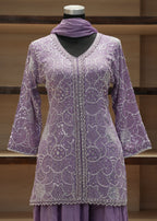 Purple embroidered dress on a mannequin against a wooden background