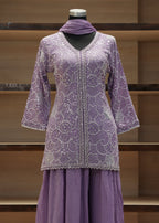 Purple embroidered outfit on a mannequin against a wooden shelf background