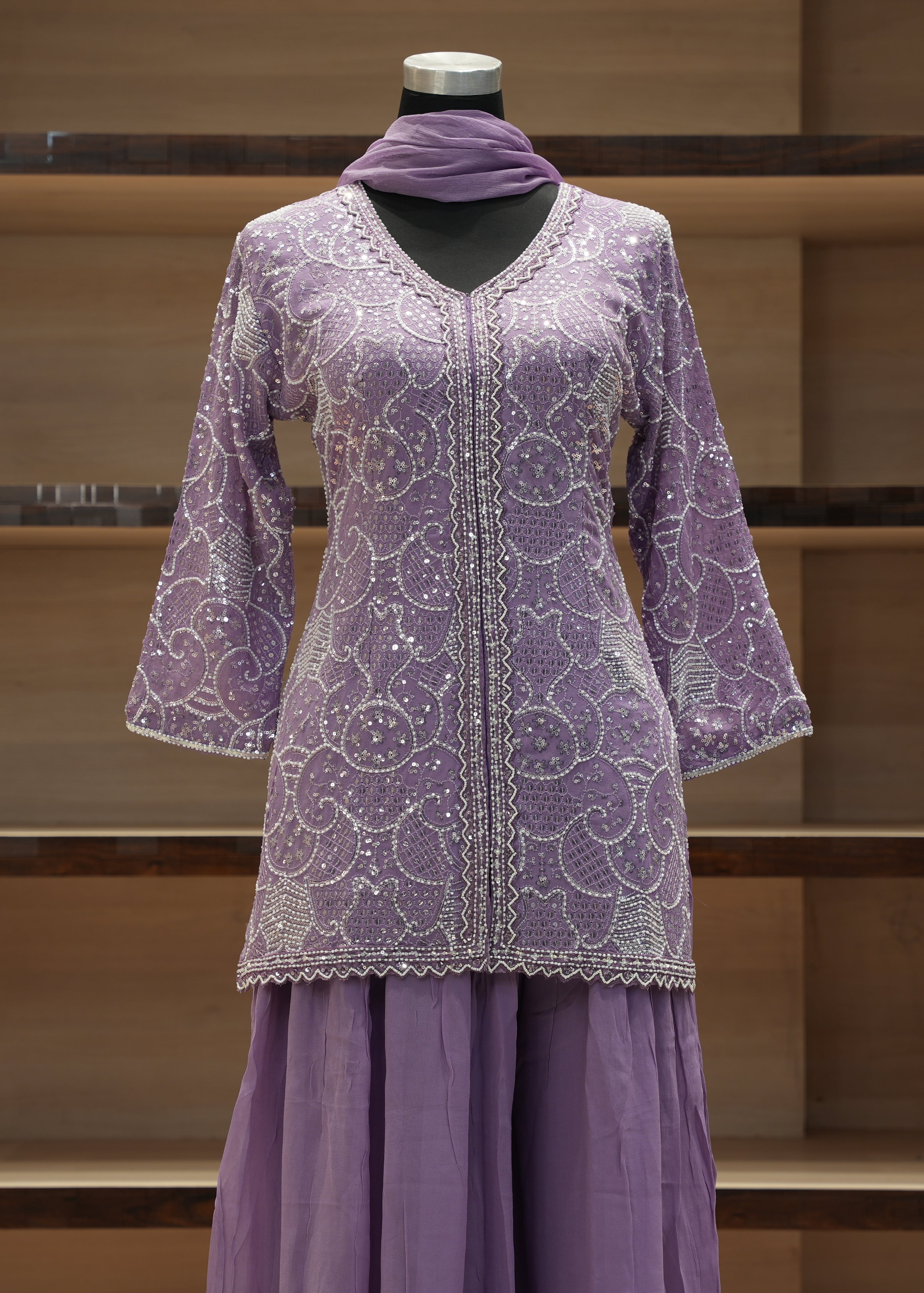 Purple embroidered outfit on a mannequin against a wooden shelf background