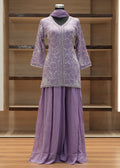 Purple outfit with intricate patterns on a mannequin against a wooden background
