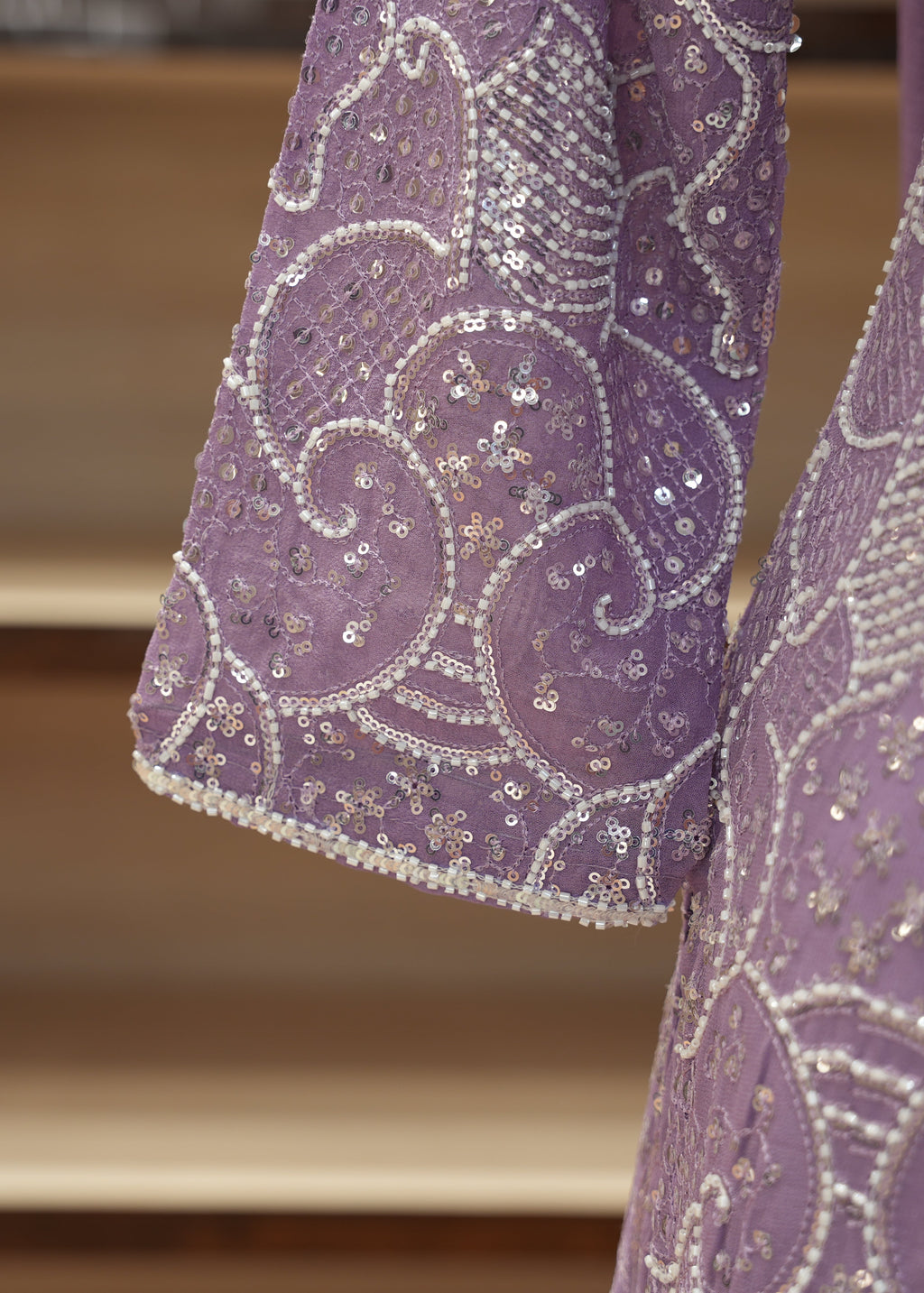 Close-up of a purple embroidered fabric with intricate patterns on a wooden surface.