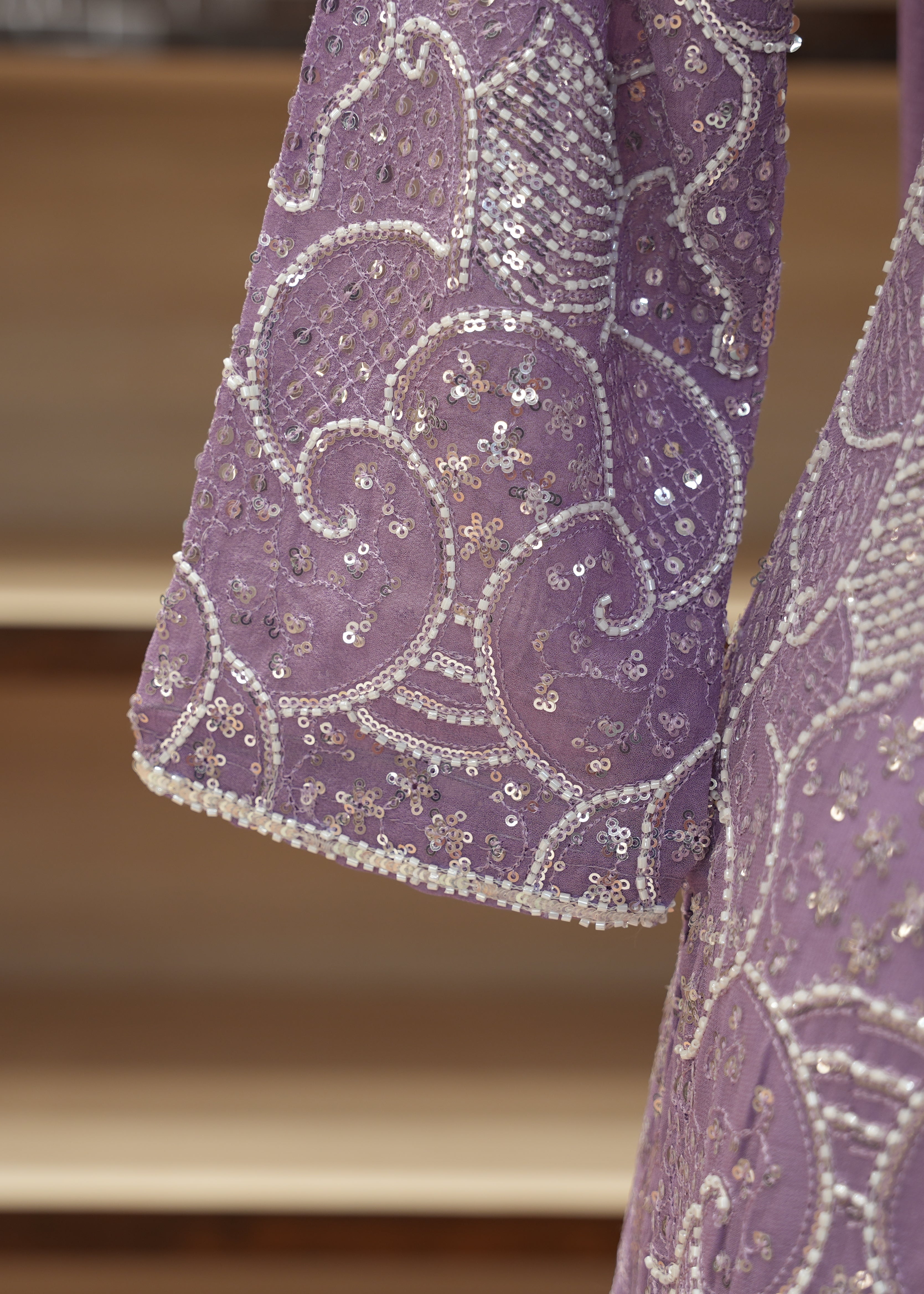Close-up of a purple embroidered fabric with intricate patterns on a wooden surface.
