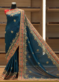 Blue saree with intricate patterns on a mannequin against a wooden background