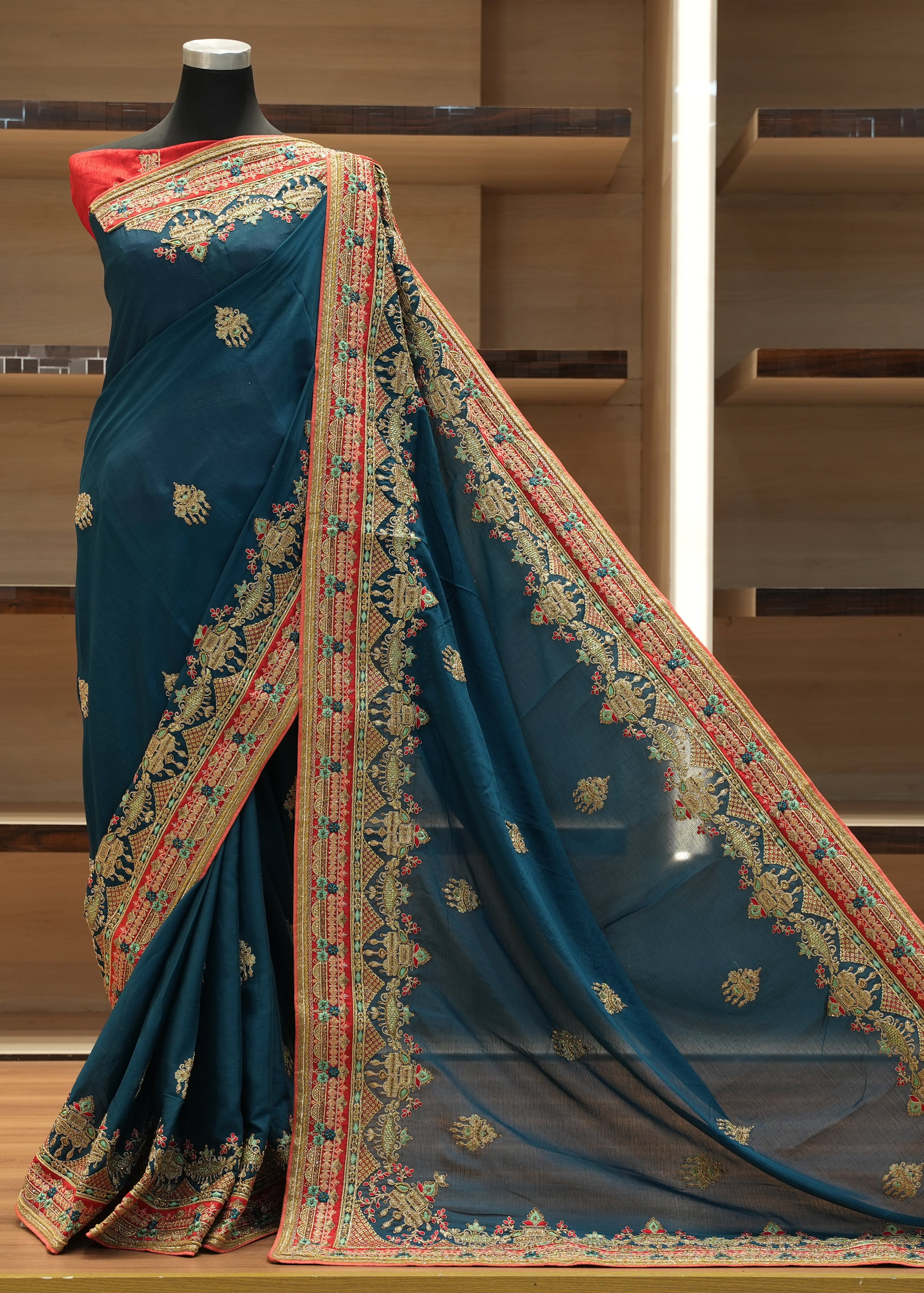 Blue saree with intricate patterns on a mannequin against a wooden background
