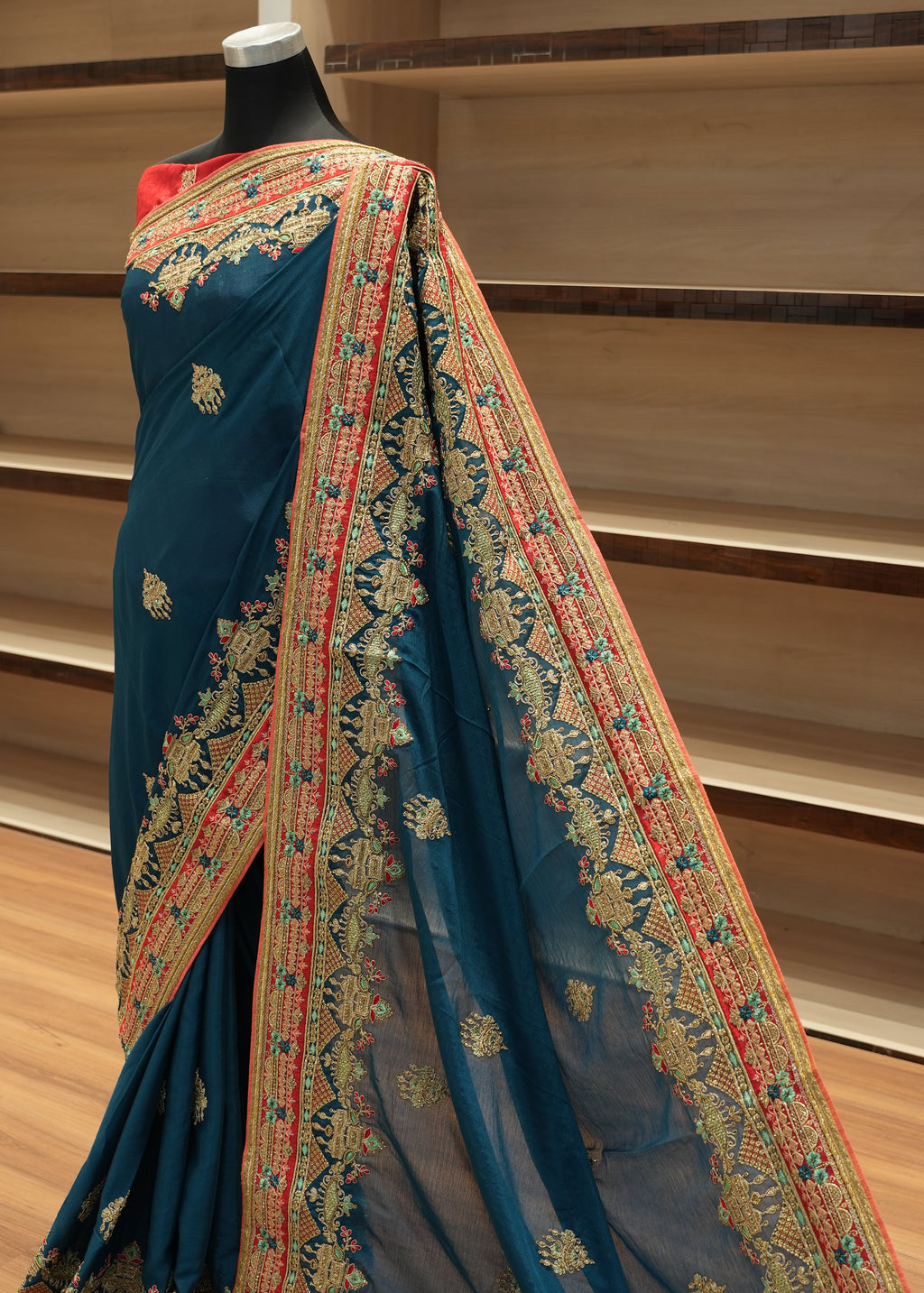 Blue saree with intricate gold and red patterns on a wooden surface