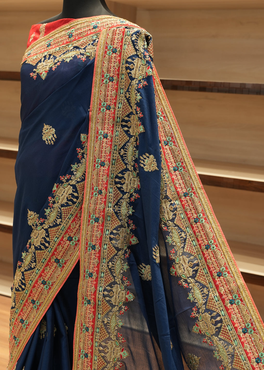 Decorative fabric with intricate patterns on a stand against a beige curtain background