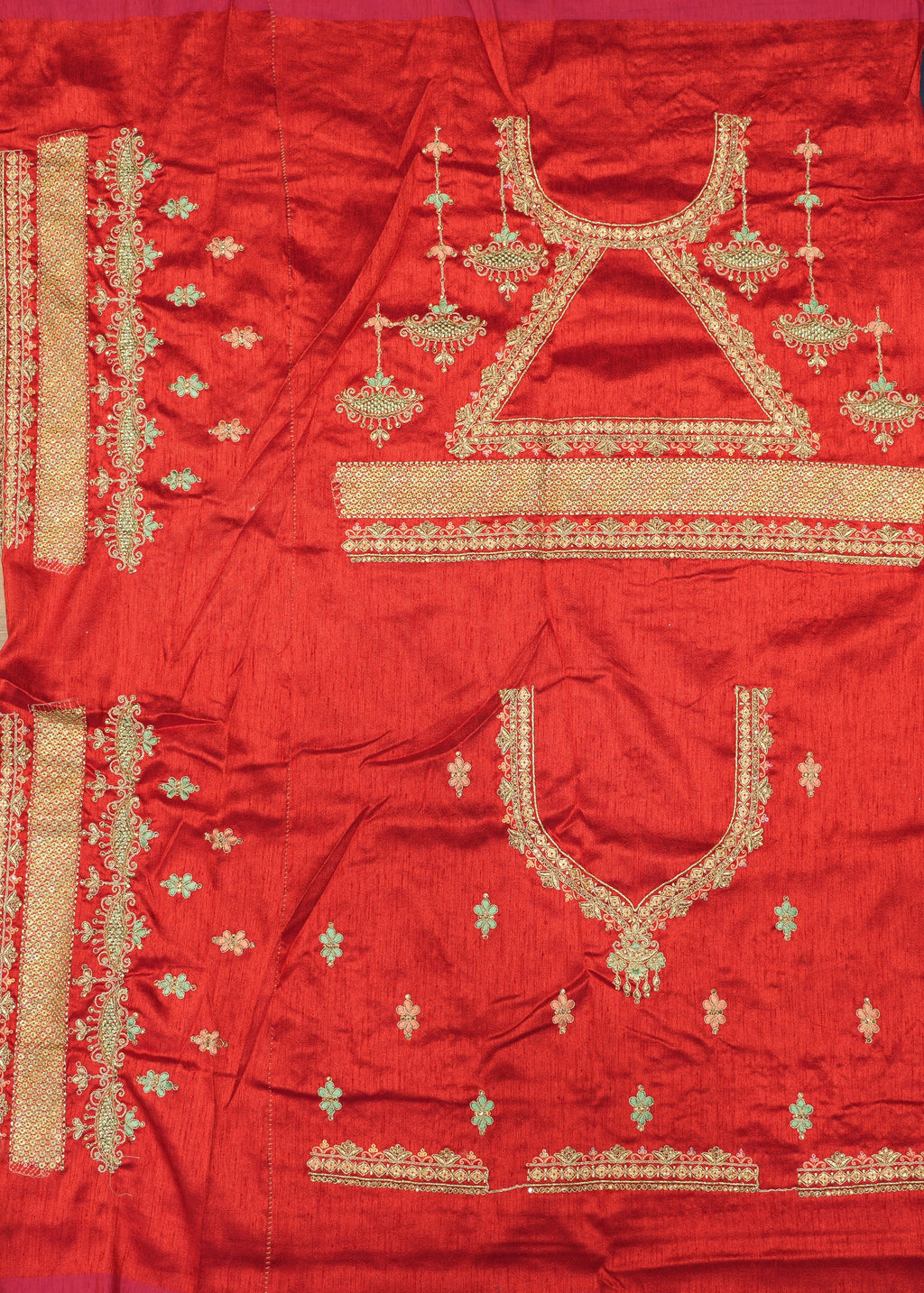 Red fabric with gold embroidery on a wooden surface