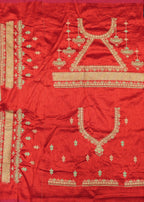 Red fabric with gold embroidery on a wooden surface