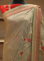Beige saree with red and green embroidery on a mannequin against a neutral background