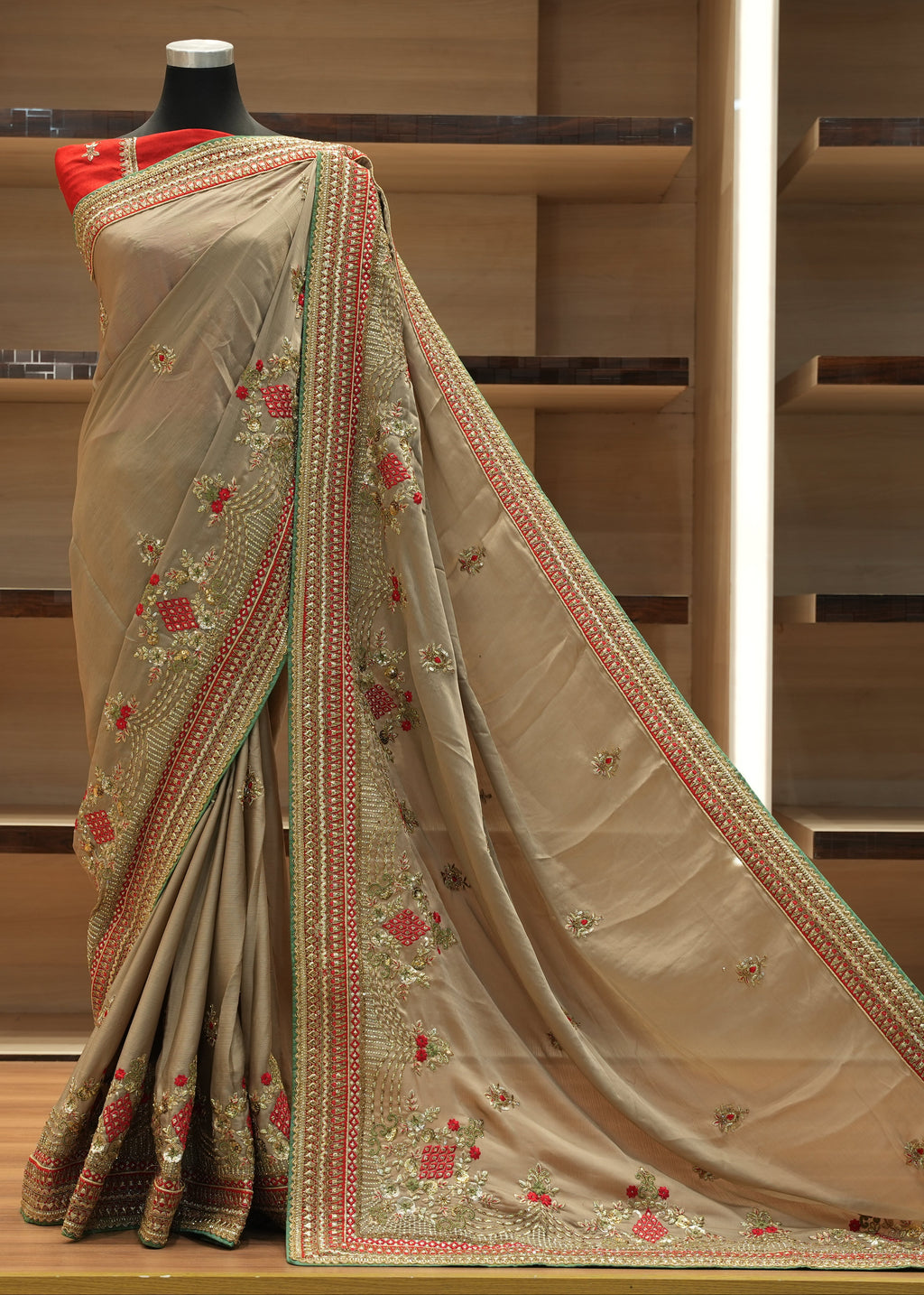 Beige saree with floral embroidery on a mannequin against a wooden shelf background