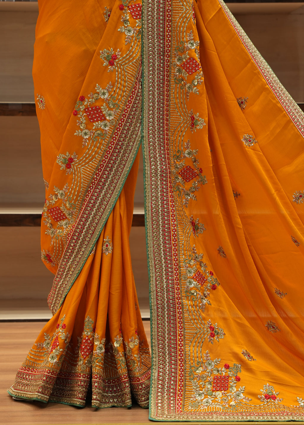Orange saree with intricate embroidery on a wooden surface