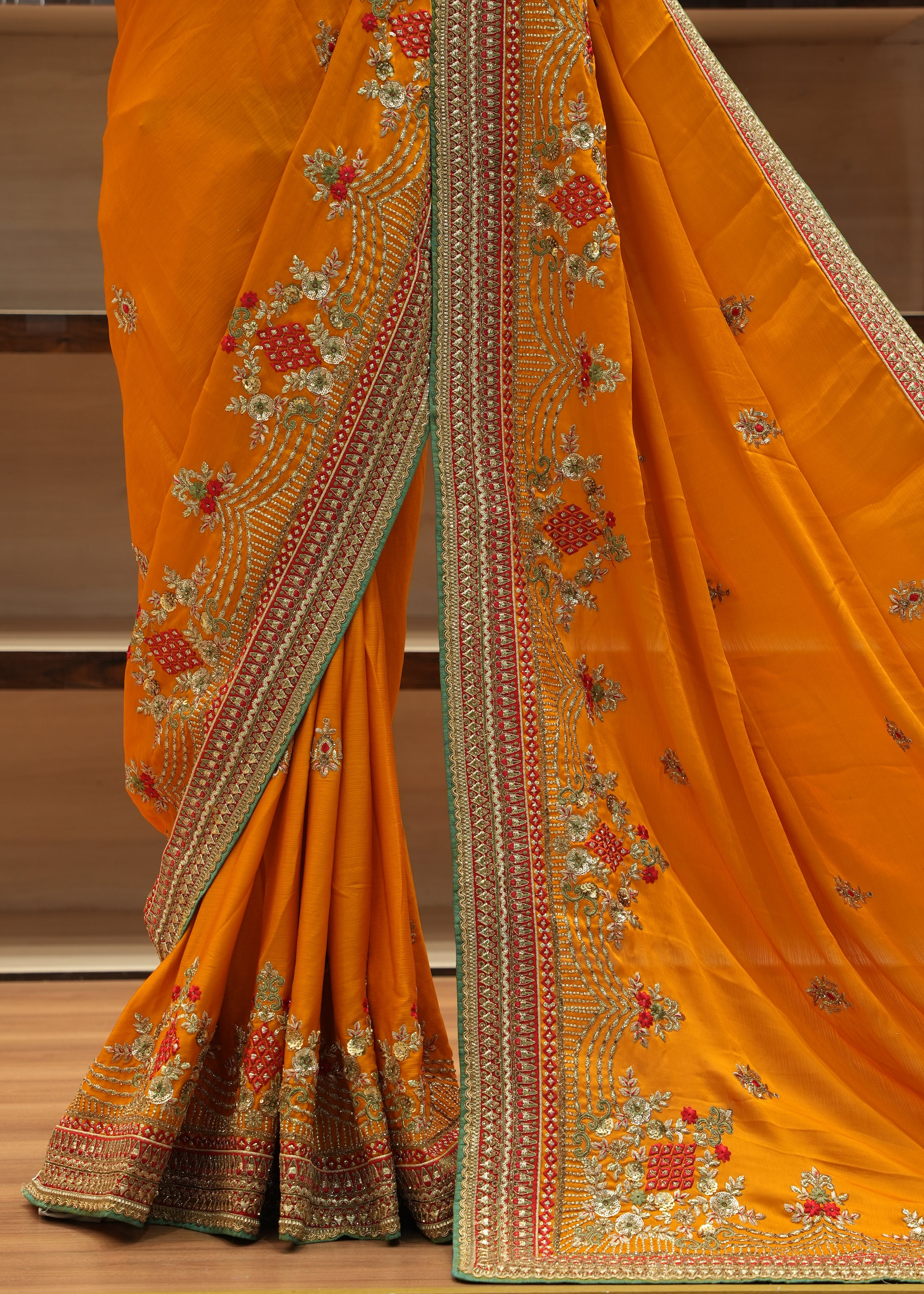 Orange saree with intricate embroidery on a wooden surface