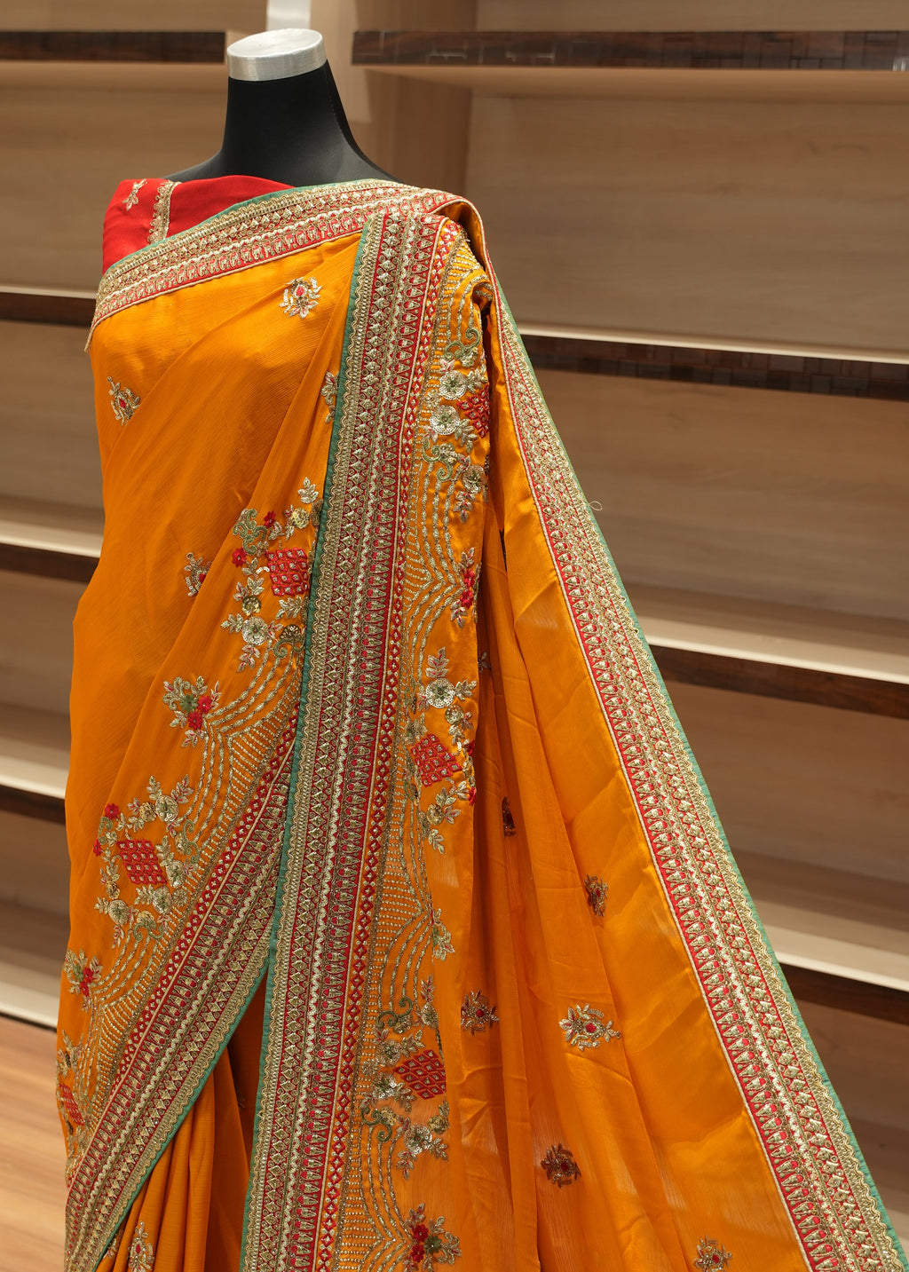 Yellow saree with intricate patterns on a wooden stand