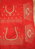 Red fabric with gold embroidery on a wooden surface