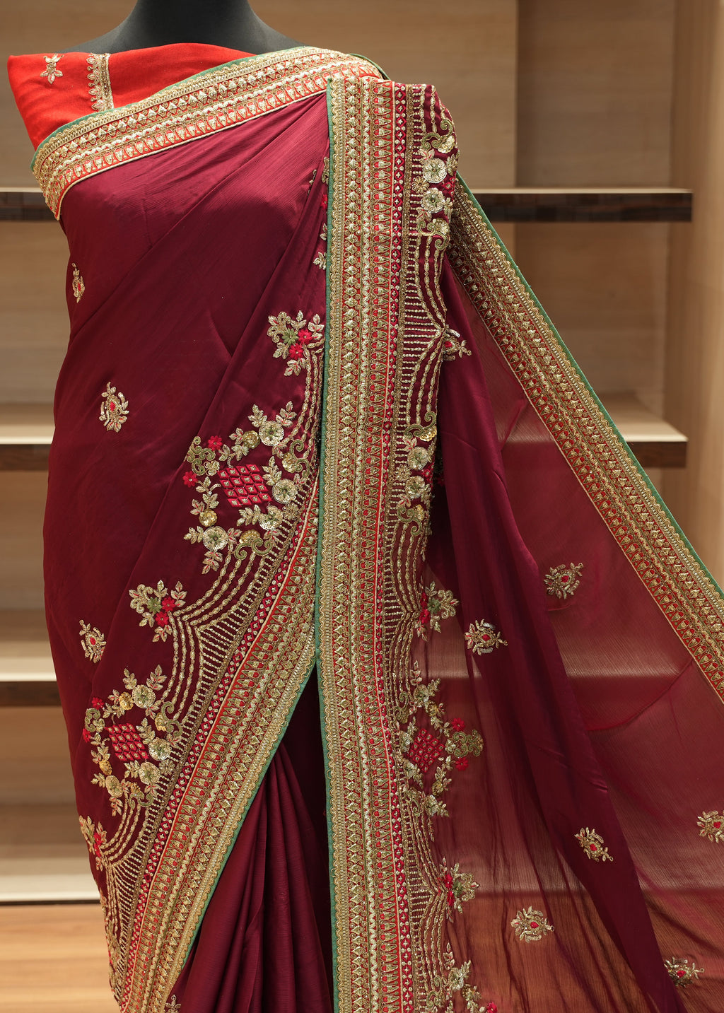 Maroon saree with gold embroidery on a mannequin against a neutral background