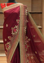 Maroon saree with gold embroidery on a mannequin against a neutral background