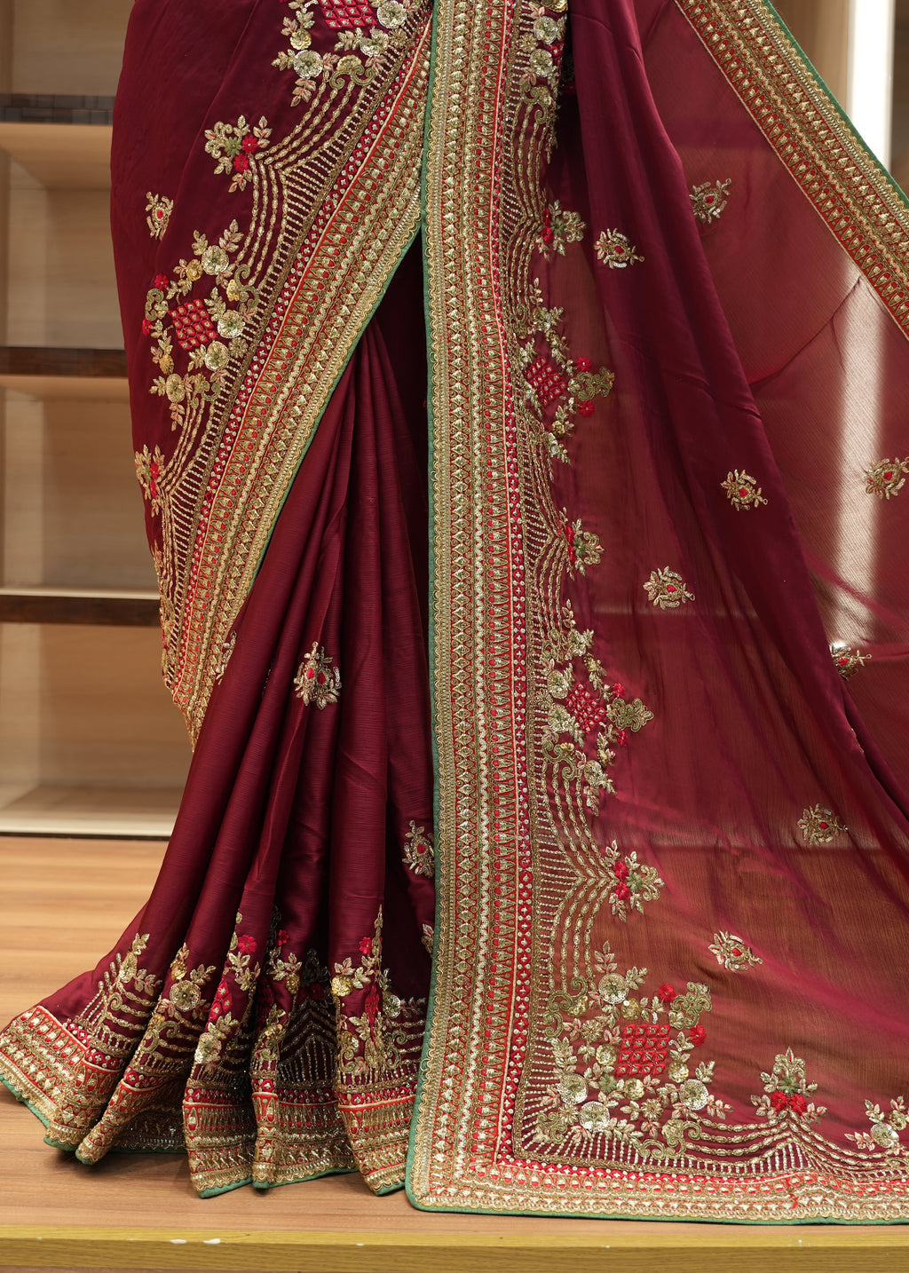 Maroon saree with gold embroidery on a wooden floor