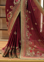 Maroon saree with gold embroidery on a wooden floor