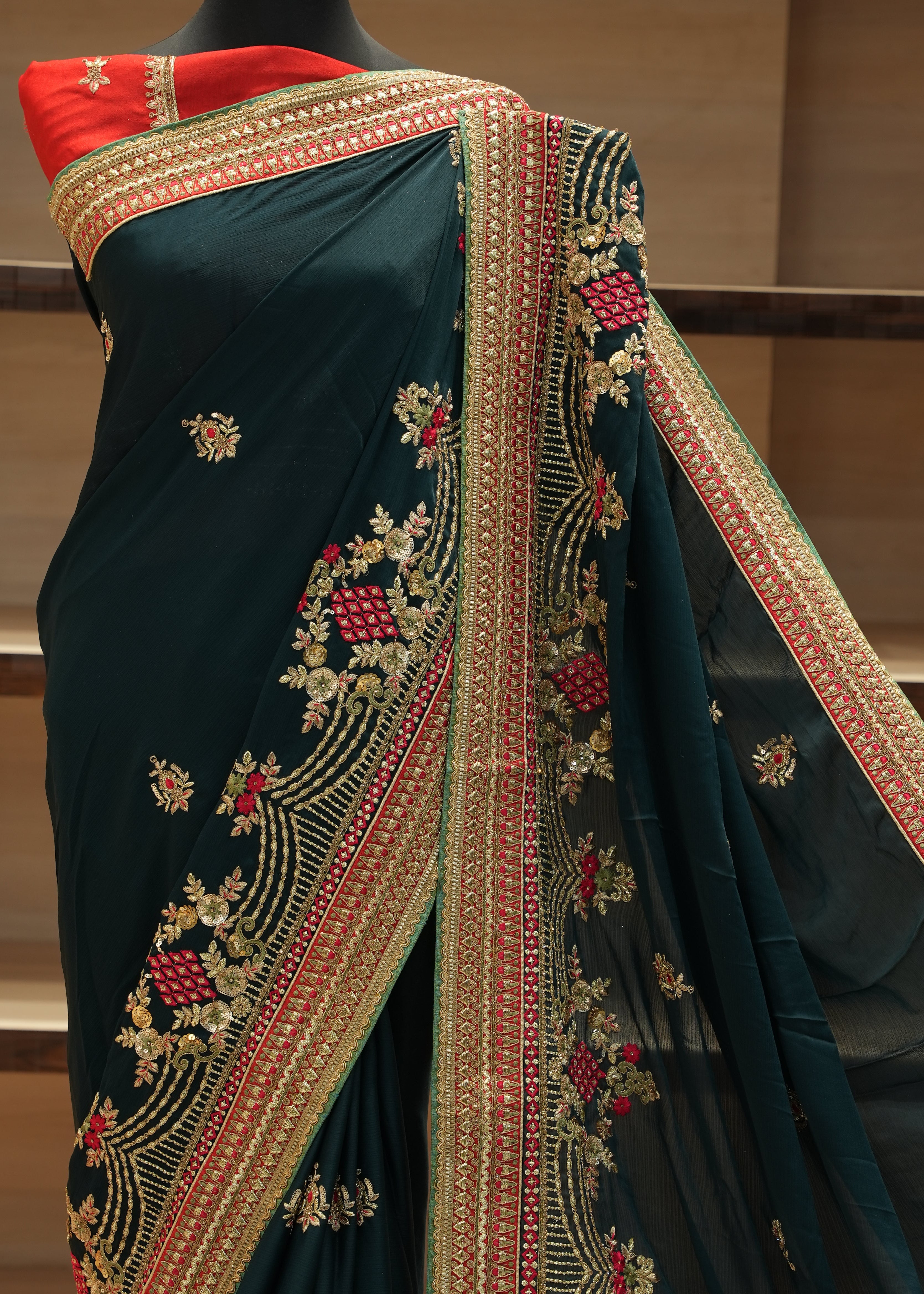 Dark green saree with red and gold border on a chair