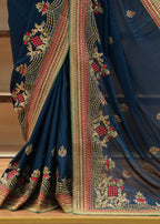 Blue saree with intricate gold and red embroidery on a wooden surface