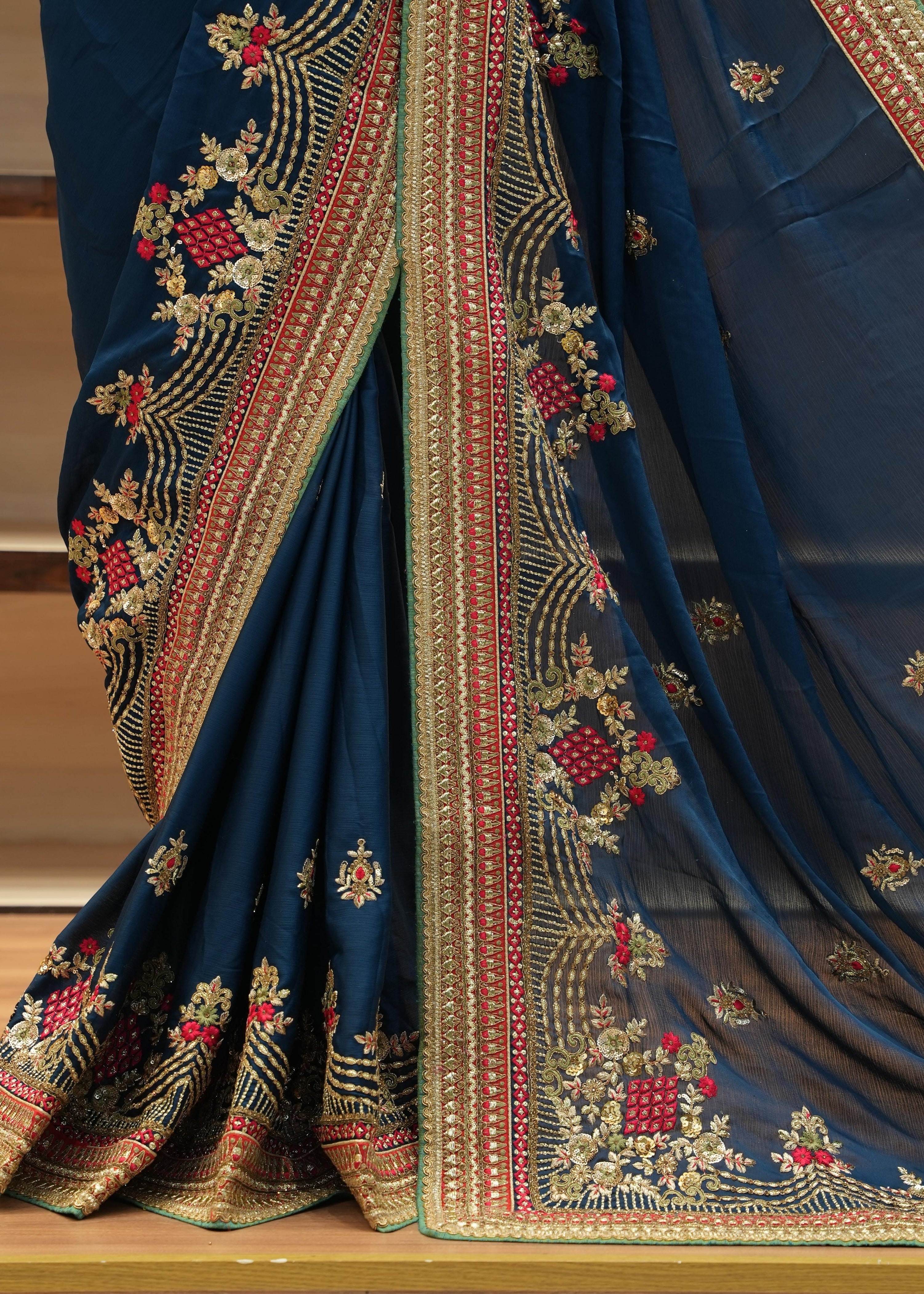 Blue saree with intricate gold and red embroidery on a wooden surface