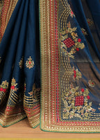 Close-up of a blue embroidered fabric with intricate patterns on a wooden surface