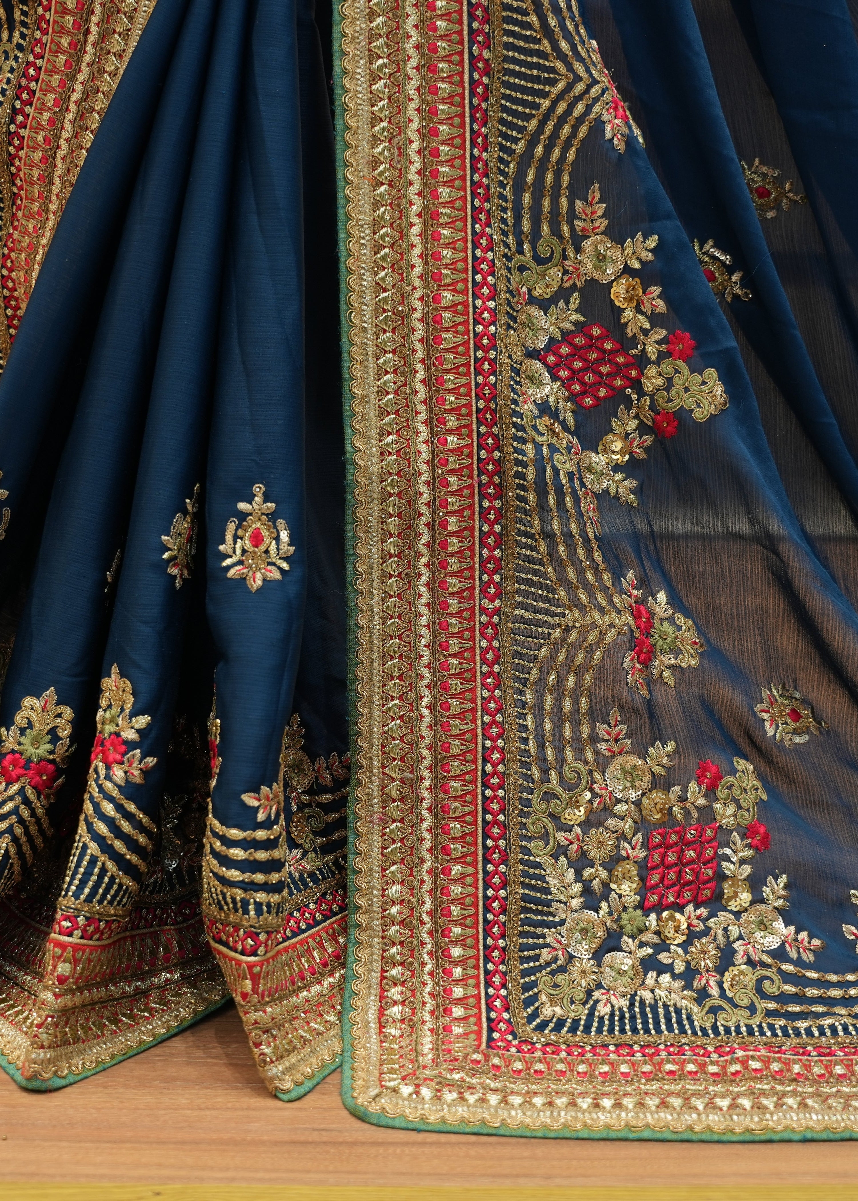 Close-up of a blue embroidered fabric with intricate patterns on a wooden surface