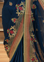 Blue saree with intricate gold and red embroidery on a wooden surface