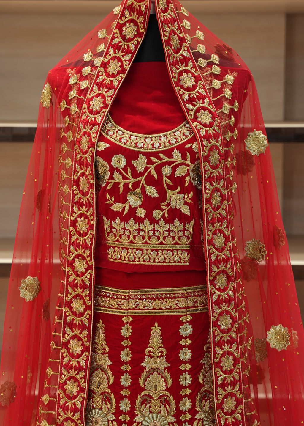 Red embroidered traditional outfit with gold detailing on a neutral background