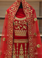 Red embroidered traditional outfit with gold detailing on a neutral background