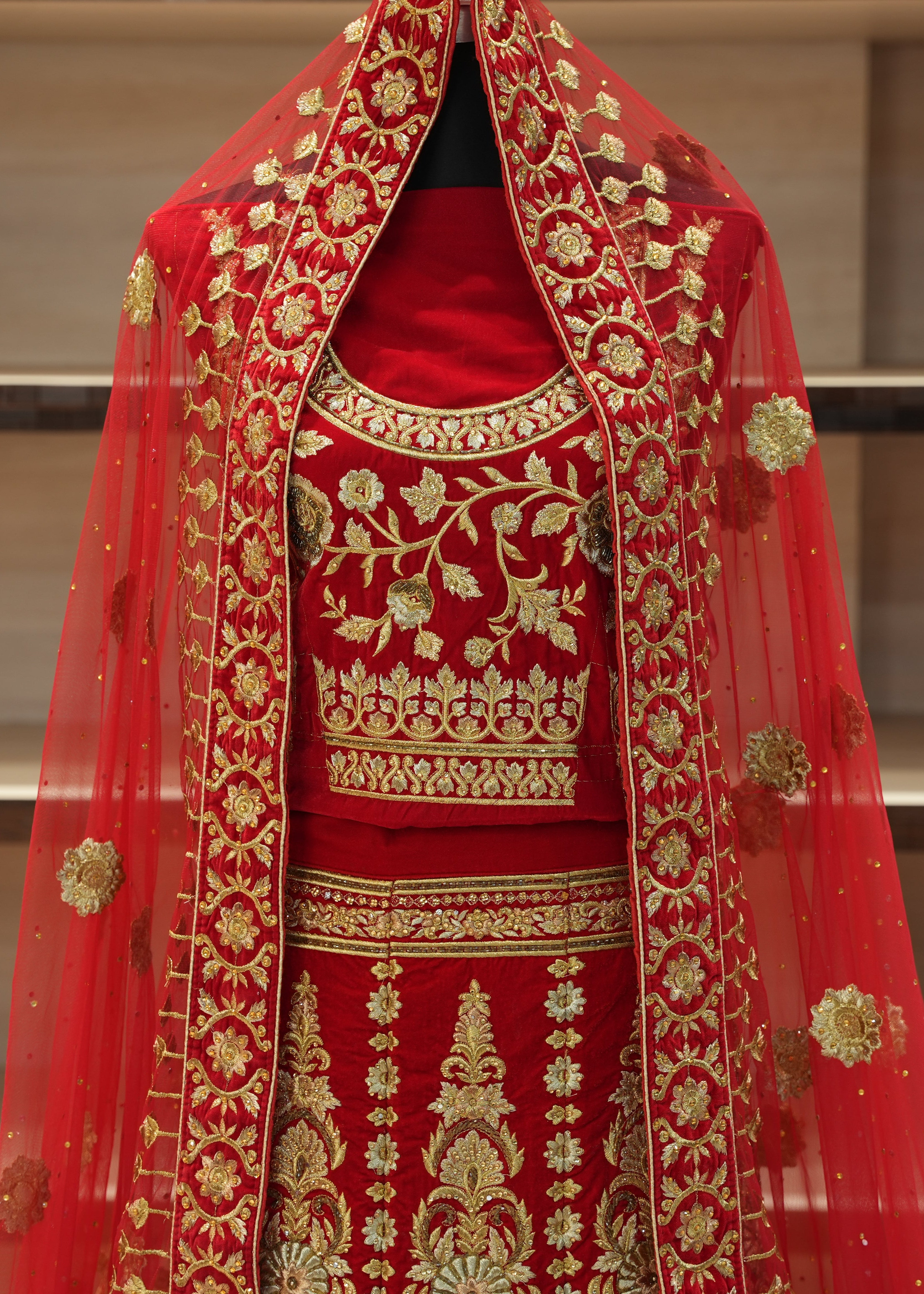 Red embroidered traditional outfit with gold detailing on a neutral background