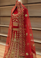 Red embroidered traditional outfit with gold details on a wooden floor.