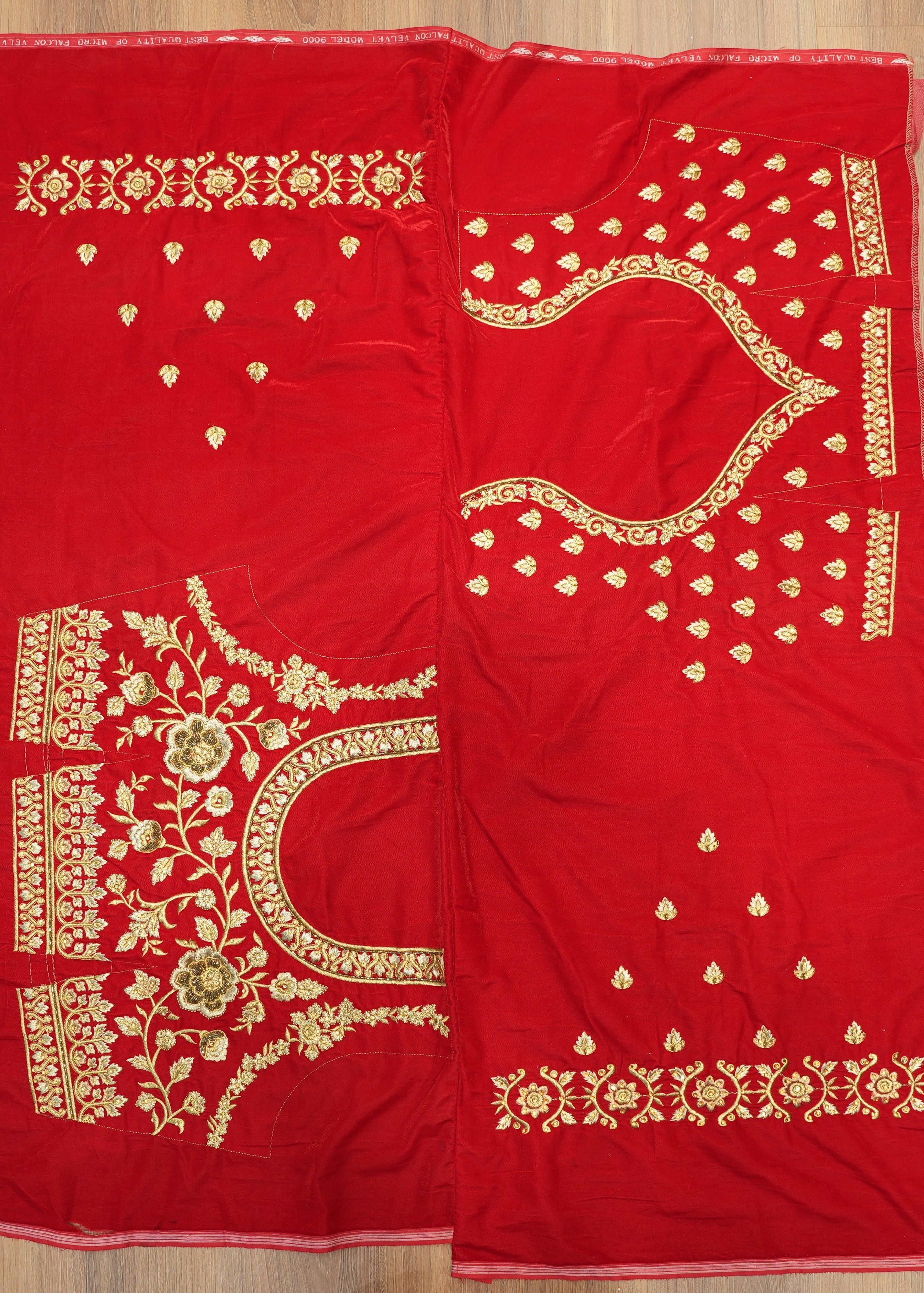 Red fabric with gold embroidery on a wooden surface