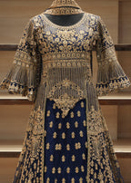 Elegant embroidered dress with gold and blue patterns on a wooden shelf.