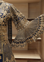 Elaborately embroidered garment with gold and blue details on a neutral background