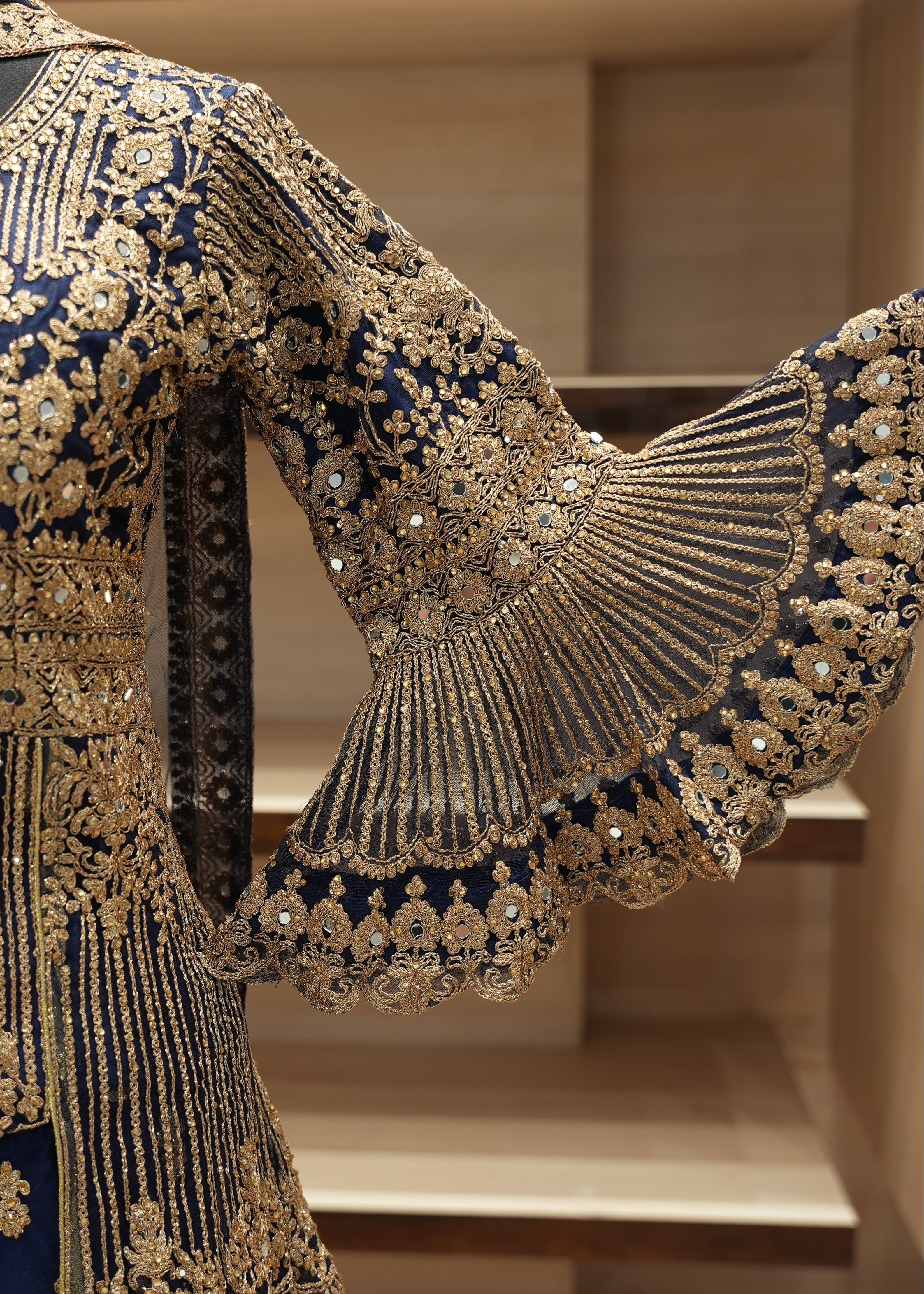 Elaborately embroidered garment with gold and blue details on a neutral background