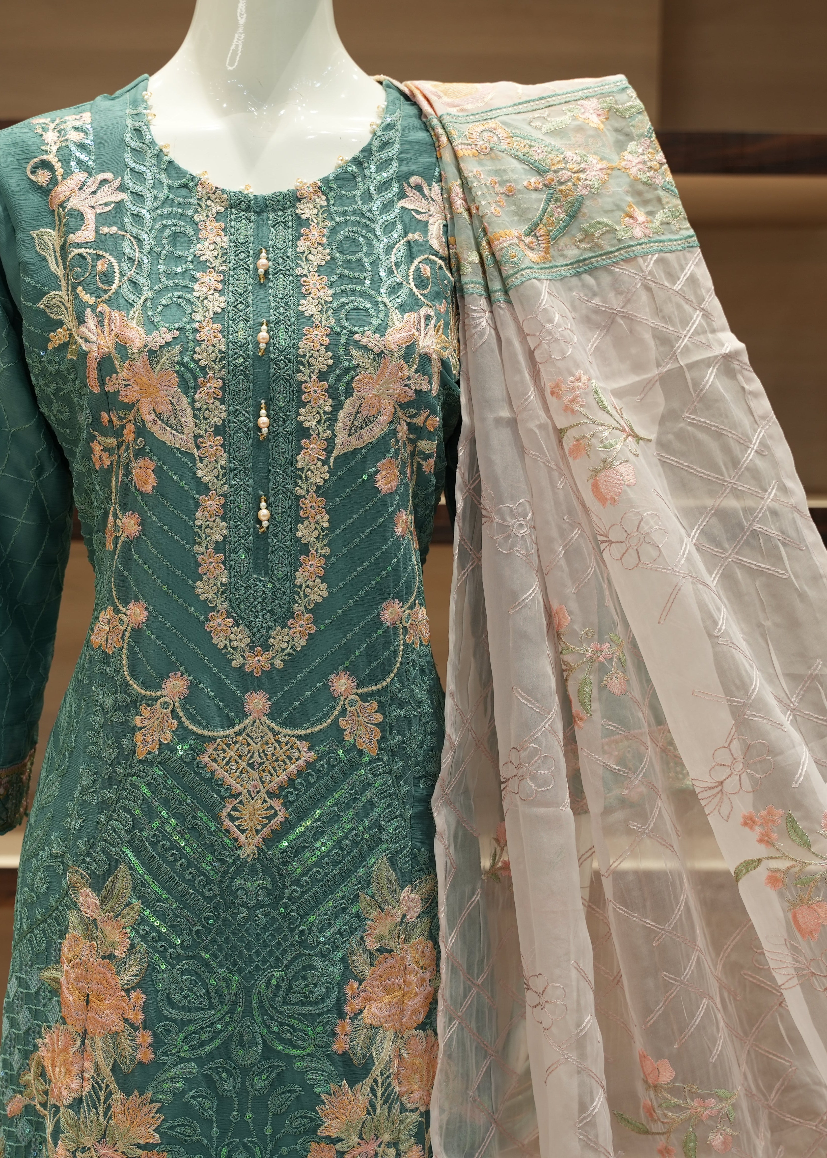 Green embroidered outfit with a sheer dupatta on a mannequin against a neutral background