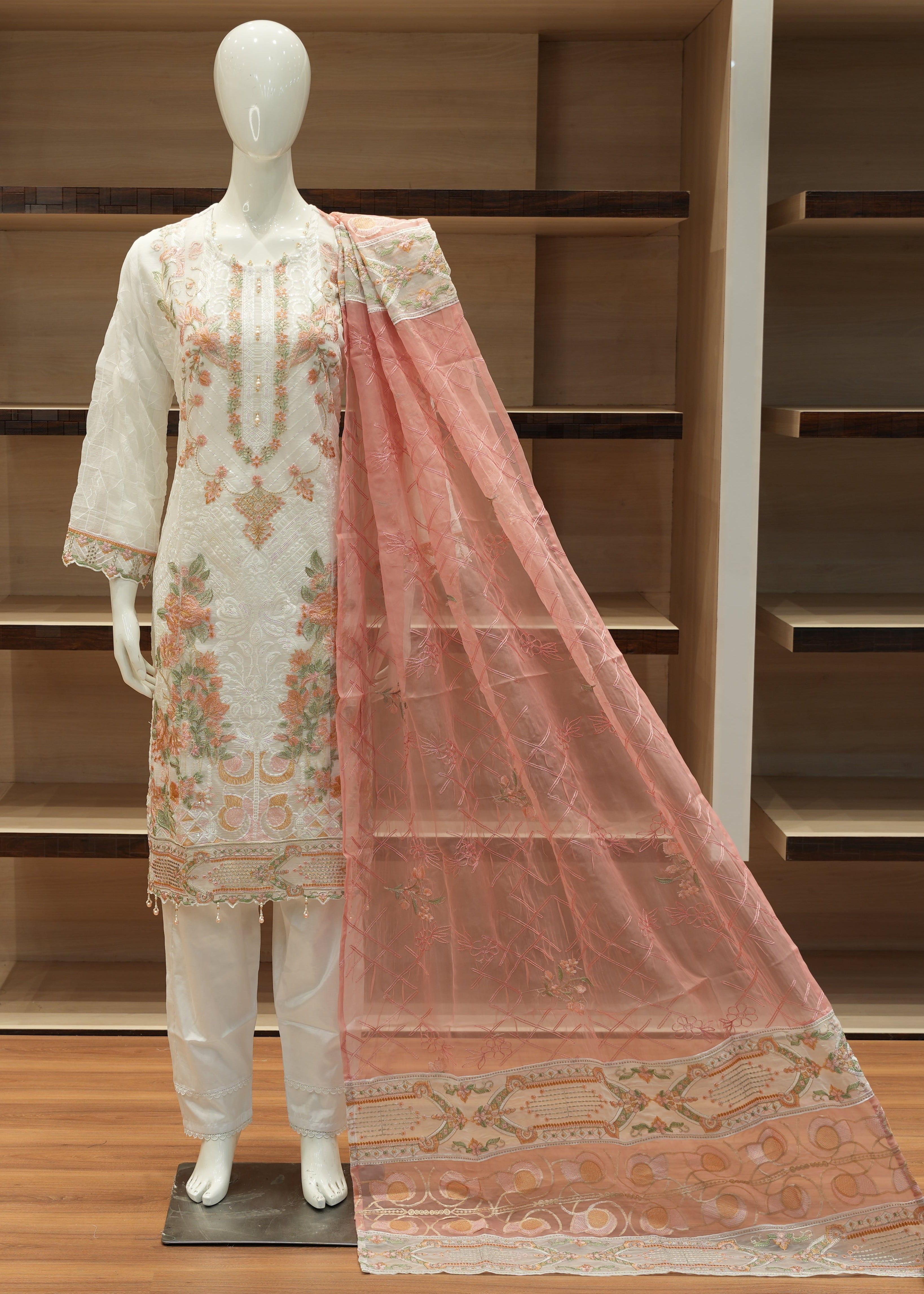 Mannequin wearing a traditional outfit with a pink dupatta in a store setting