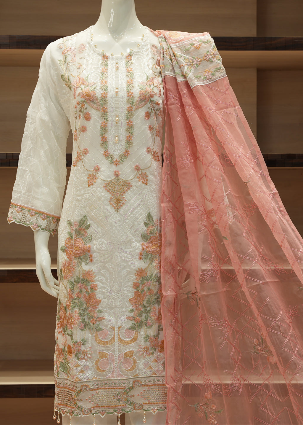 Embroidered dress with a pink dupatta on a mannequin against a neutral background